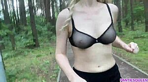 O femeie blondă face exerciții în aer liber în parc, expunându-și corpul gol și sânii săritori