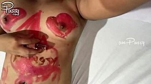 فتاة في سن المراهقة ترسم على جسدها الآسيوي العاري مع أحمر الشفاه في فيديو منزلي